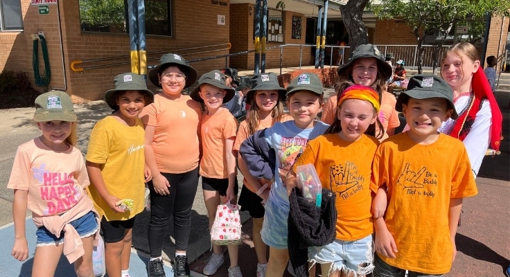 A group of students pose for a photo outside. They are dressed in orange for our annual Harmony Day.