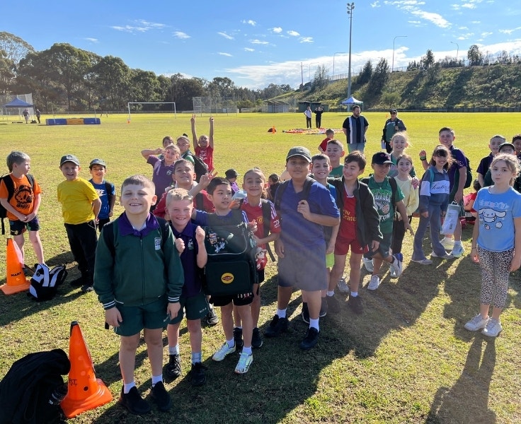 A group of students poses for a photo on an athletics field.