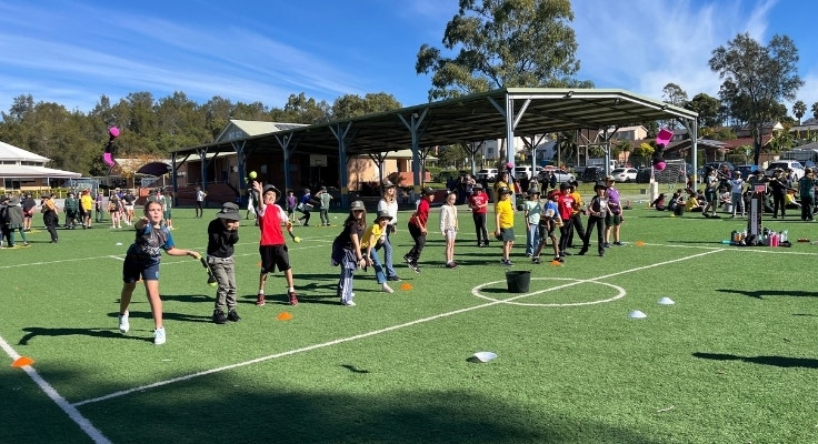 A group of students stand in a line and are throwing bean bags as part of the BSBF Indigenous Games Day.